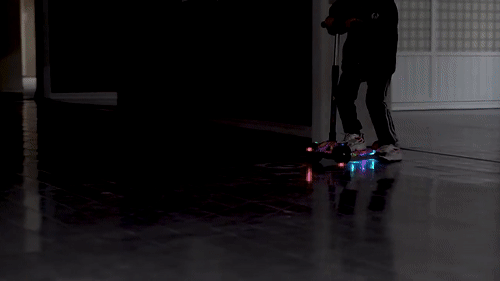 a teenager rides the scooter which is glowing with bright lights