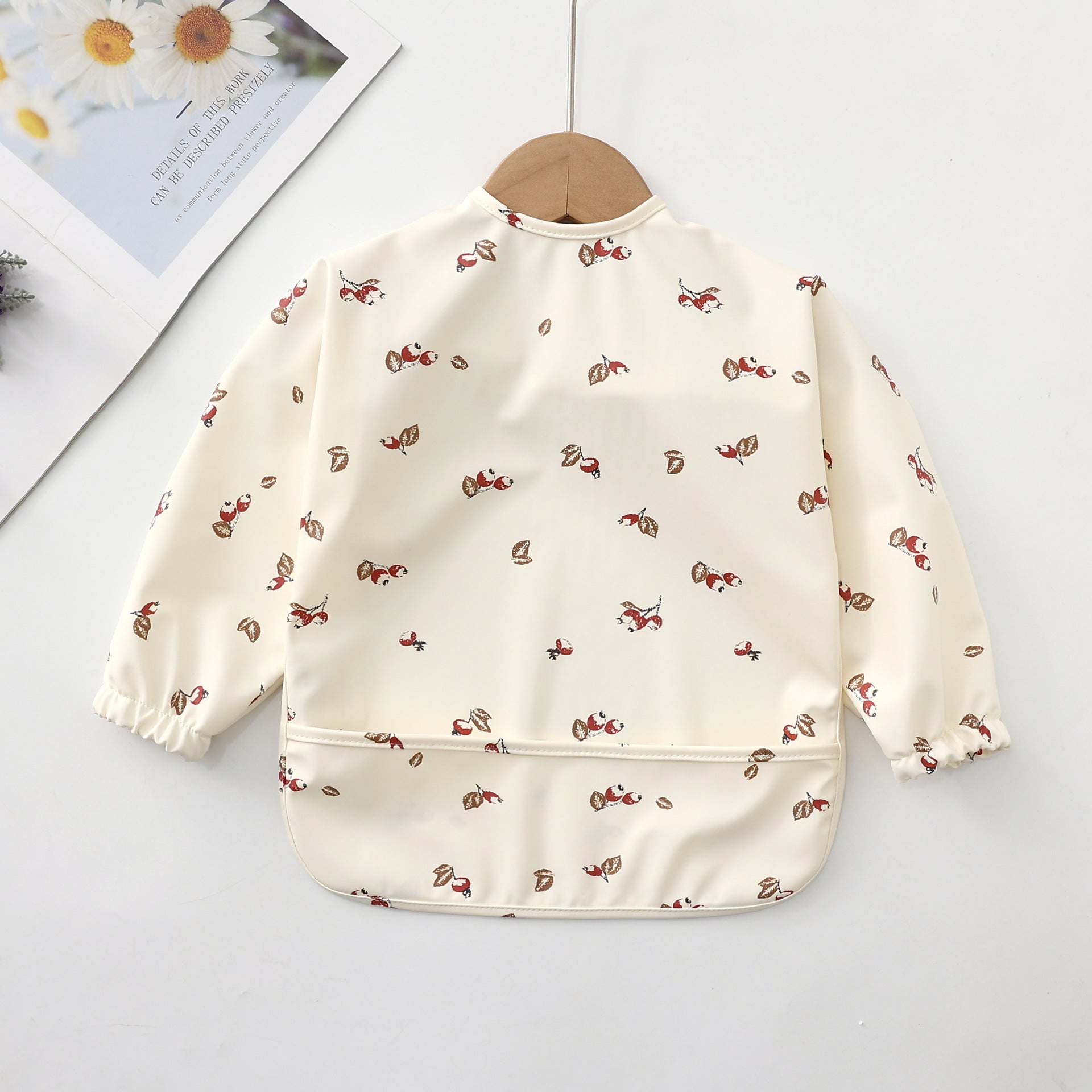 children's bib with hawthorns printed on a white background. The apron bib has a dirty white background