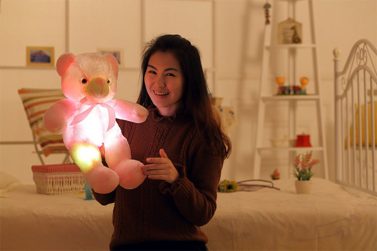 a girl happily holds a light up pink teddy bear