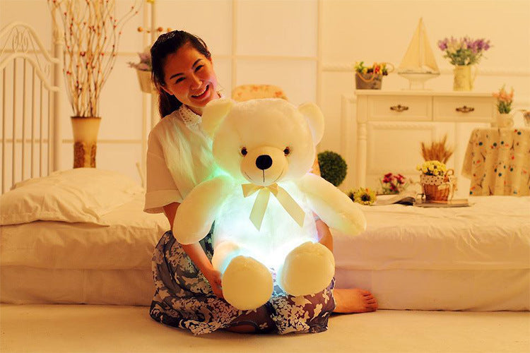 a girl happily sits with a light up yellow bear