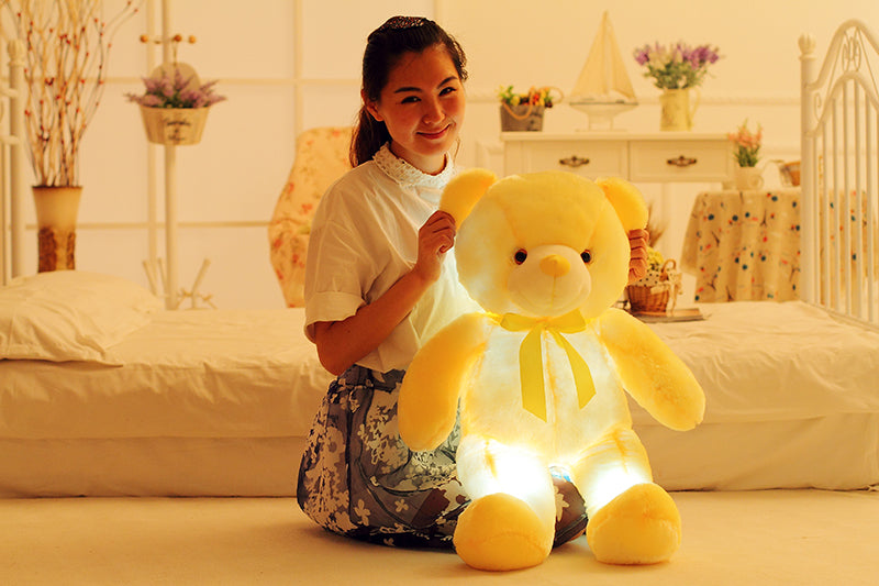 a girl poses alongside a big yellow teddy bear