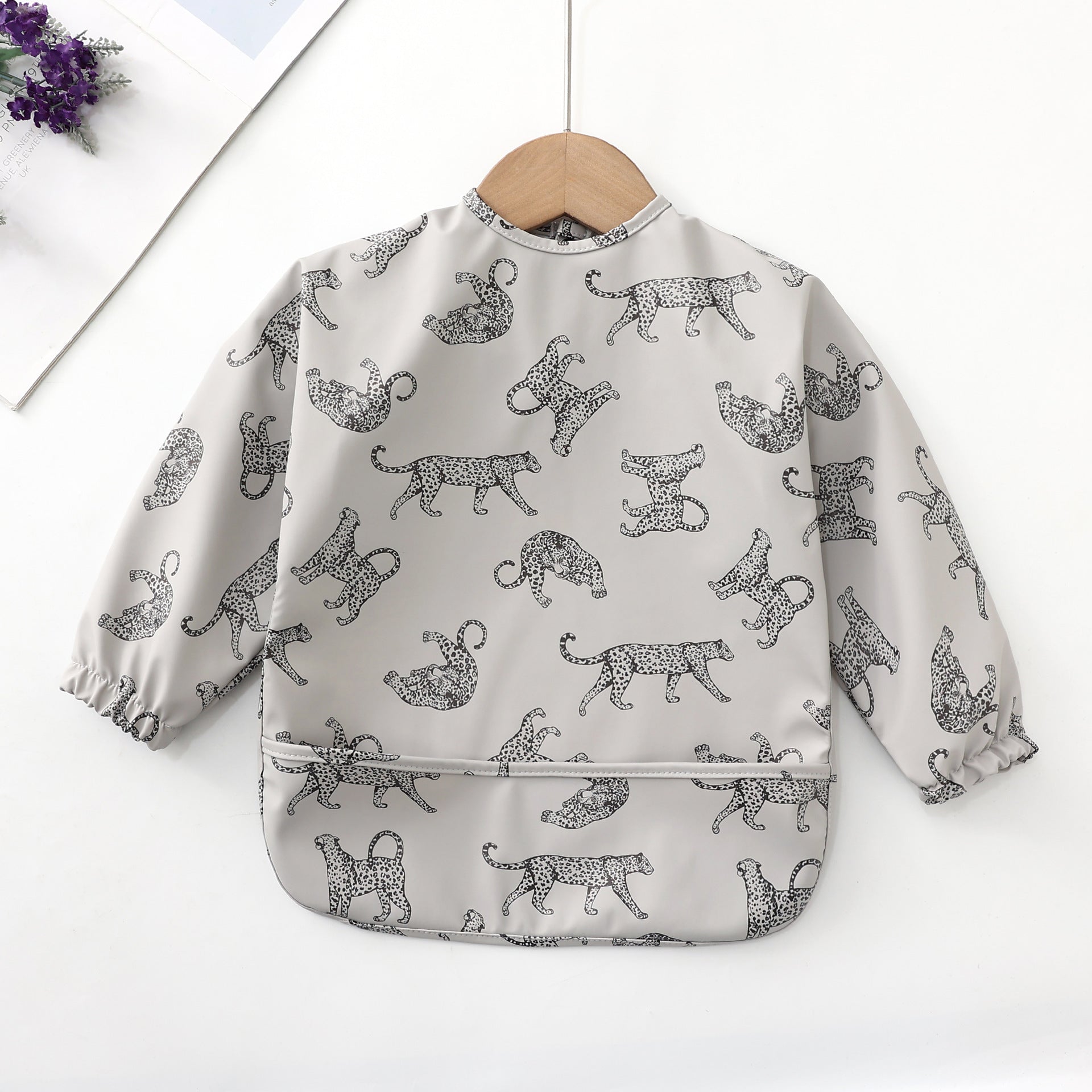apron bib for baby boys to help when eating. The bib is printed with leopard pictures and has a black and white color for easy detection of food stains