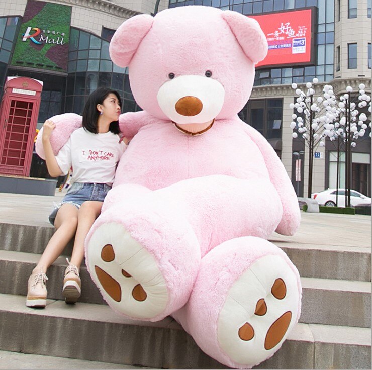 a girl stands with a huge pink teddy bear