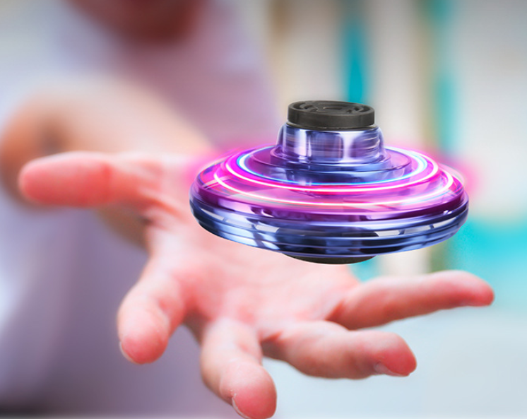 a hand plays with a spinner which is floating slightly above the air