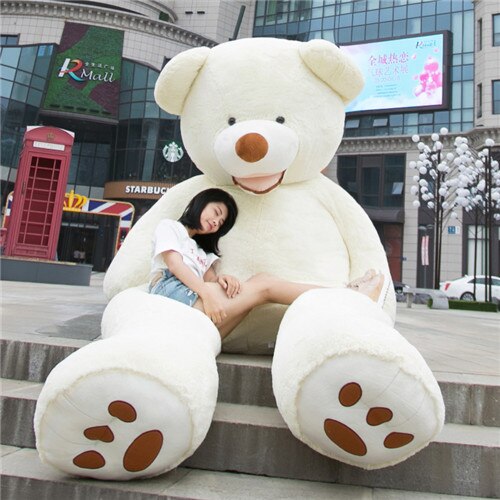 a girl sitting with a giant plush soft teddy bear with white skin and brown leather nose